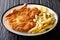 Fried veal cutlet Milanese with lemon and French fries close-up