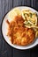 Fried veal cutlet Milanese with lemon and French fries close-up. Vertical top view