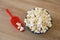 Fried white airy popcorn in a decorative plate and in a red spoon on brown wooden background