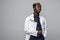 Friendly Afro-American doctor holding a clipboard and smiling at the camera on gray