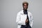 Friendly Afro-American doctor holding a clipboard and smiling at the camera on gray