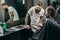 Friendly barber smiling while client showing screen of smartphone
