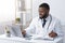 Friendly black doctor making online check up, using laptop