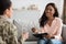 Friendly black psychologist lady talking with soldier woman during therapy session