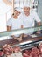 Friendly Butchers Standing At Meat Counter