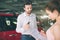 Friendly car salesman talking to a young woman and showing a new car inside showroom Signing of contract