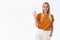 Friendly, carefree sassy attractive blond woman in orange t-shirt, pants raise palm and waving hand in greeting gesture