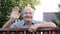 Friendly caucasian old man waving hi or farewell, isolated outdoors background with green trees and fence