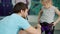 Friendly climbing instructor helping child with safety harness indoors in gym