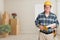 Friendly Contractor With Plans in Hard Hat In Empty Room with Moving Boxes