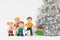 Friendly doll family with a puppy and a lush silver Christmas tree, the concept of a family holiday