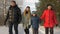 Friendly family holding hands and walking in snowy forest at cold winter day