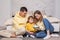 Friendly family, lovely parents with child son sitting by the bed and holding bowl with popcorn