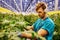 Friendly farmer working on hydraulic scissors lift platform in greenhouse