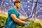 Friendly farmer working on hydraulic scissors lift platform in greenhouse