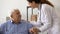 Friendly female caregiver give support older male with severe diagnosis