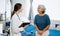 Friendly Female Head Nurse Making Rounds does Checkup on Patient Resting in Bed. She Checks tablet while Man Fully Recovering