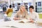 Friendly female tutor helping to diligent positive girl preparing for exam in library