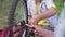 friendly grandfather and grandson repair bicycle wheel together with tools while sitting in garden backdrop of green