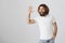 Friendly guy volunteering to help. Studio shot of handsome kind eastern man with beard and curly hair tilting while