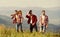 Friendly guys with guitar hiking on sunny day. Enjoying freedom together. Group of young people in checkered shirts