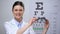 Friendly lady optician shoving optical trial frame to camera, eyesight testing