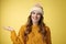 Friendly-looking confident pleasant attactive young european woman wearing winter hat, sweater extend arm show product