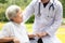 Friendly male asian doctor greeting recovering,encouraging,comforting senior woman patient,doctor with stethoscope holding hand of