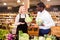 Friendly middle aged saleswoman helping African man to choose fresh cabbage in organic food store