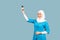 A friendly, muslim doctor or nurse woman in hijab with a stethoscope on a blue background. emotions of victory or success