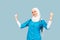 A friendly, muslim doctor or nurse woman in hijab with a stethoscope on a blue background. emotions of victory or success