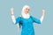 A friendly, muslim doctor or nurse woman in hijab with a stethoscope on a blue background. emotions of victory or success