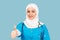 Friendly, muslim doctor or nurse woman in hijab with stethoscope showing thumb up over blue background. emotions of victory or