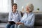 Friendly nurse laughing with elderly female patient during homecare visit