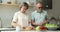 Friendly older age spouses talk while preparing breakfast at kitchen