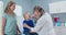 Friendly pediatrician examining child patient with sore throat while mom watches