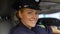 Friendly policewoman smiling and looking to camera, sitting in patrol car, order