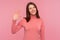 Friendly positive woman with brown hair waving her hand showing hi gesture, welcoming and greeting