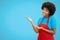 Friendly presenting african american waitress with red apron on blue background