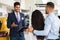 Friendly sales assistant having conversation with couple at car showroom