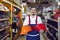 Friendly salesman demonstrates two colored safety helmets in industrial warehouse store.