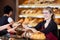 Friendly saleswoman in bakery passing bread