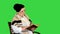 Friendly senior woman sitting in chair reading a book on a Green Screen, Chroma Key.