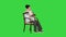 Friendly senior woman sitting in chair reading a book on a Green Screen, Chroma Key.