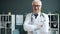 Friendly smiling doctor standing alone in clinic looking at camera with happy face