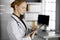 Friendly smiling female doctor using clipboard in clinic. Portrait of friendly physician woman at work. Medical service