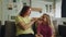 A friendly smiling mother sits on the sofa in the room with her daughter and braids her hair for preparation to the