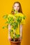 Friendly smiling young woman buying a leafy green ficus plant holding a large potted specimen in her hands at a retail nursery