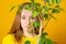 Friendly smiling young woman buying a leafy green ficus plant holding a large potted specimen in her hands at a retail nursery