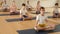 Friendly sporty family of young parents and teenage kids doing yoga together in fitness studio, sitting on mats in lotus